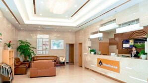A hotel lobby with a reception desk, seating area, and a large plant. - Greentree Inn Jiangsu Suzhou Zhangjiagang Tangshi Town Yangzi Road Express Hotel (Suzhou)