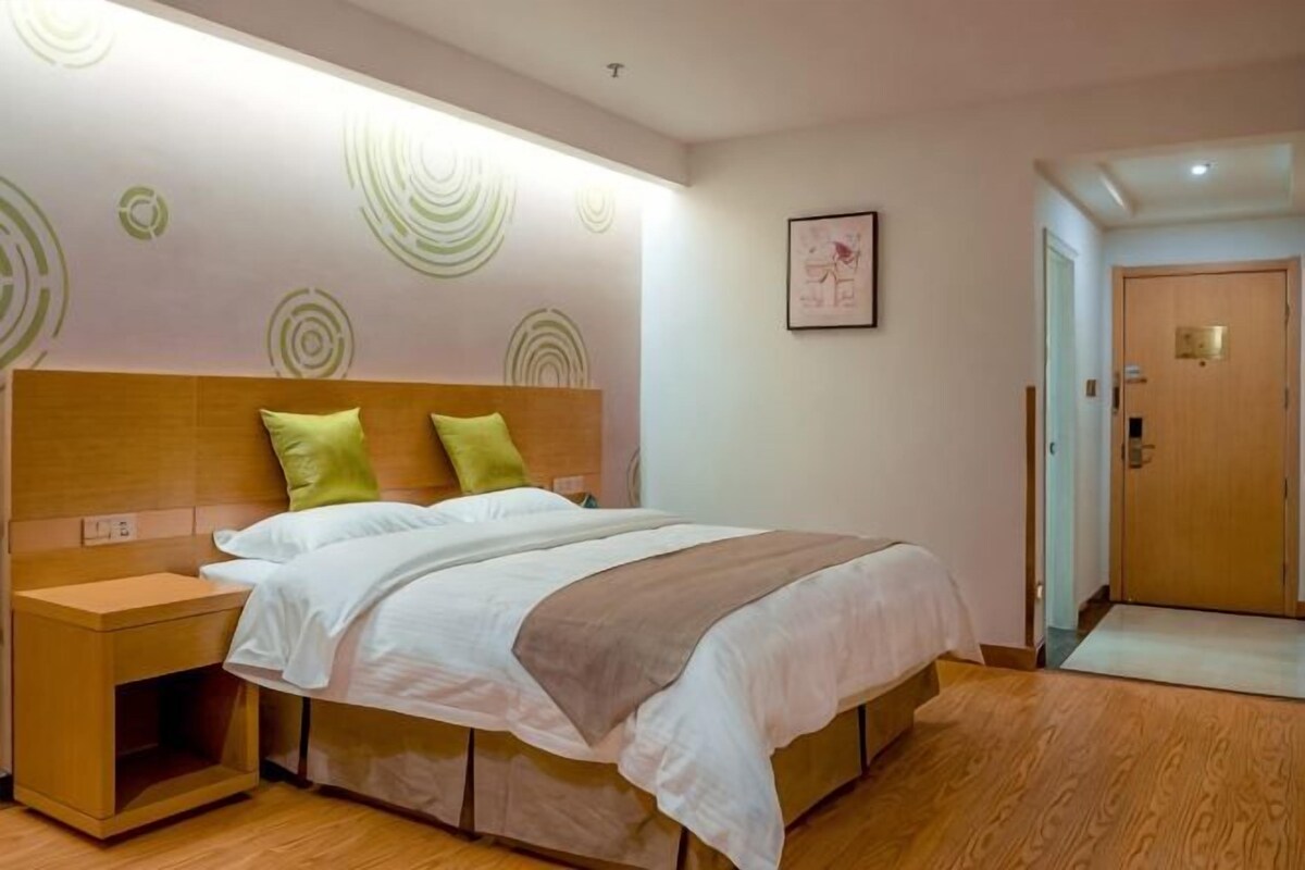 A hotel room with a bed, nightstand, and a door leading to another room.