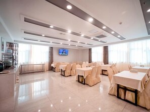 A hotel conference room with multiple tables and chairs, a flat-screen TV, and a large window. - Greentree Inn Jiangsu Suzhou Zhangjiagang Tangshi Town Yangzi Road Express Hotel (Suzhou)