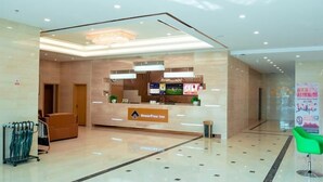 A modern reception area with a glass partition, a reception desk, and a green chair. - Greentree Inn Jiangsu Suzhou Zhangjiagang Tangshi Town Yangzi Road Express Hotel (Suzhou)