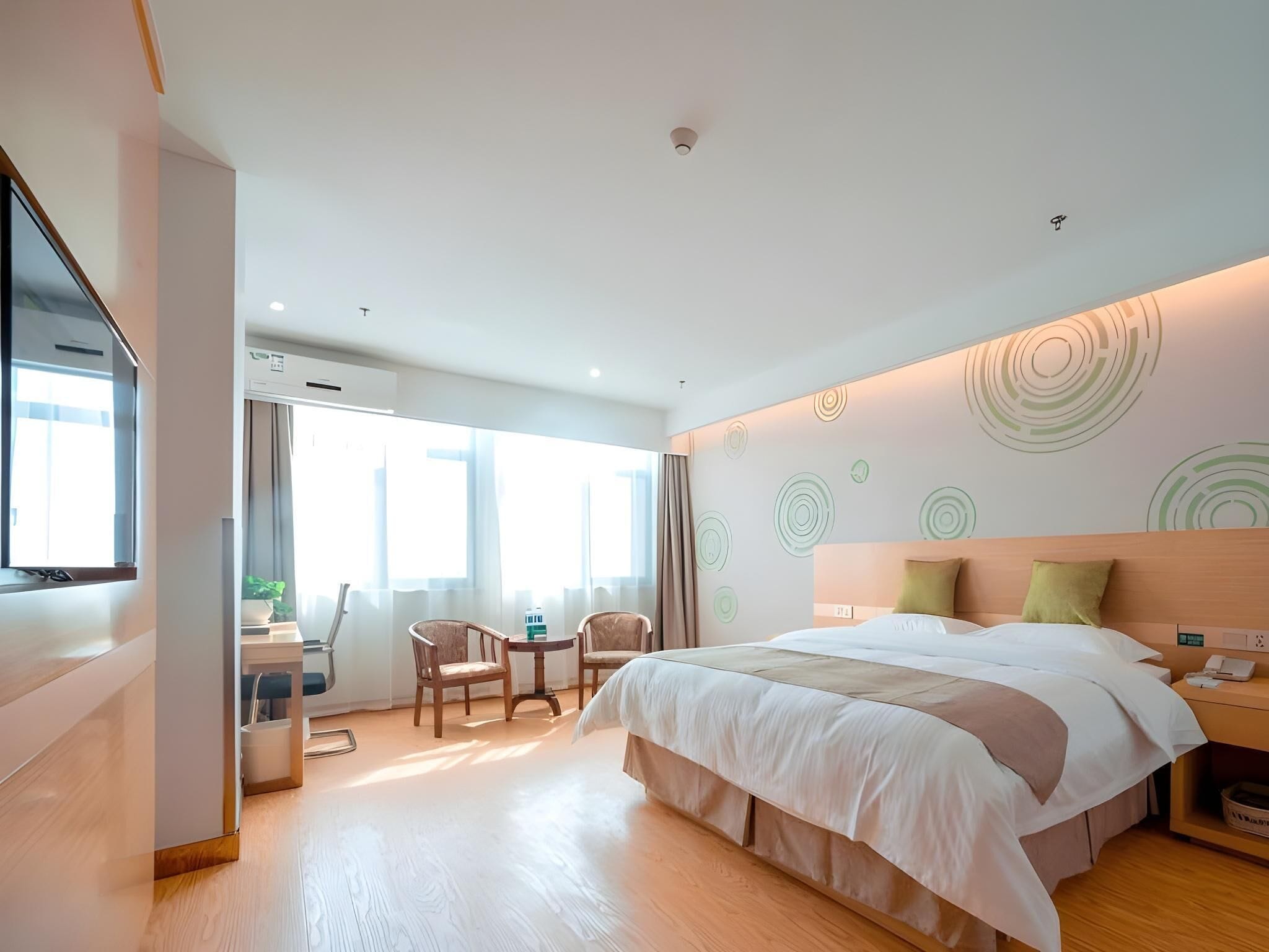 Una habitación de hotel moderna con una cama grande, un escritorio con una silla y una mesita.