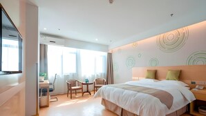 A modern hotel room with a large bed, a desk with a chair, and a small table. - Greentree Inn Jiangsu Suzhou Zhangjiagang Tangshi Town Yangzi Road Express Hotel (Suzhou)