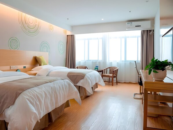 A hotel room with two beds, a desk, a chair, and a large window.