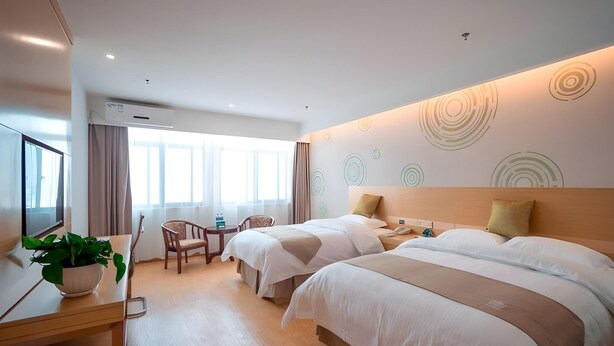 A hotel room with two beds, a desk with a plant, a TV, and a window with curtains. - Greentree Inn Jiangsu Suzhou Zhangjiagang Tangshi Town Yangzi Road Express Hotel (Suzhou)
