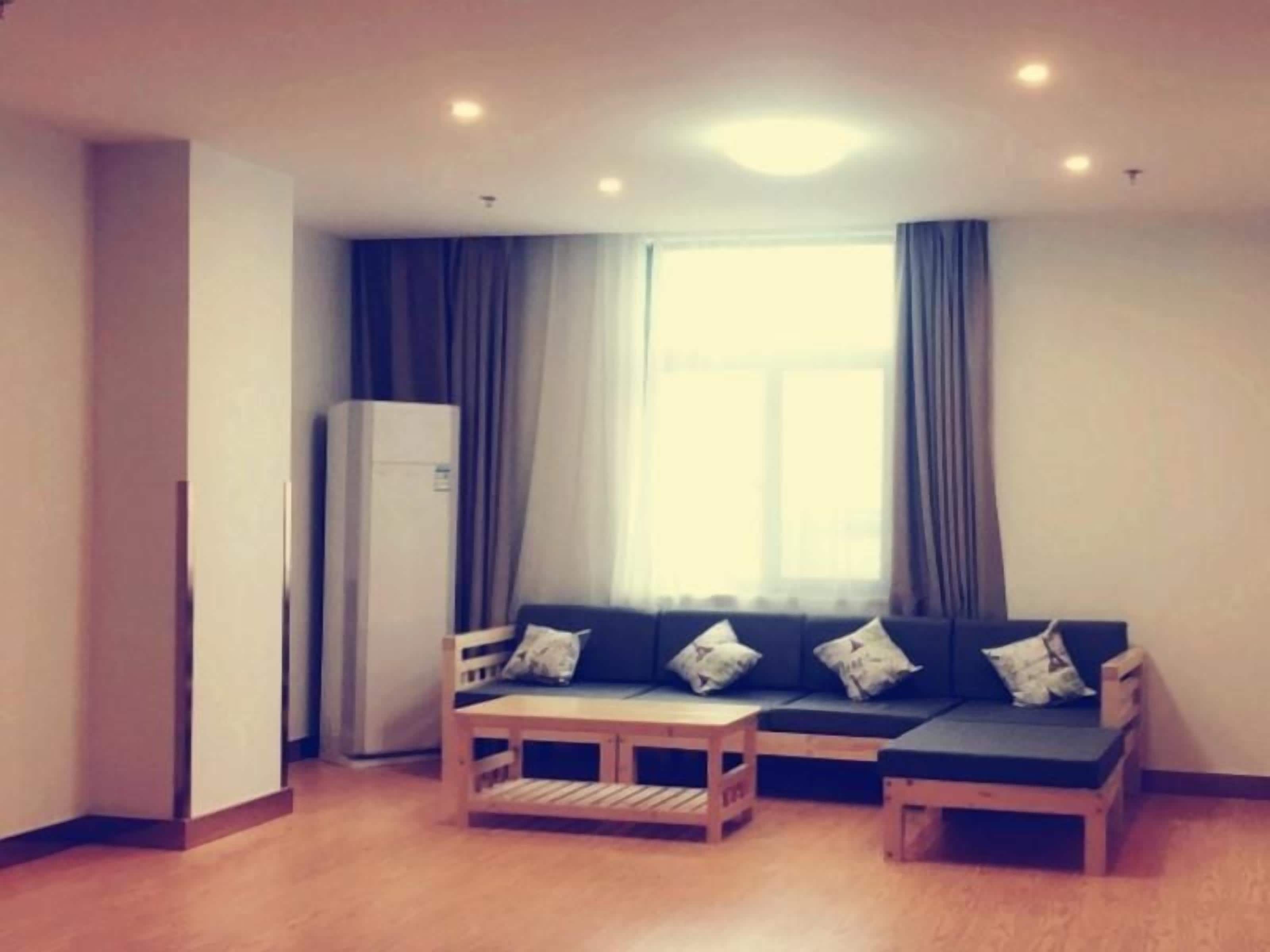 Una habitación con sofá, una mesita y un refrigerador.