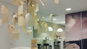 A reception area with a counter, hanging notes, and a painting of a rural scene. - Hello Villarreal Suites (Villarreal)