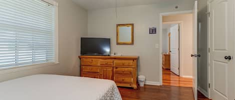 A bedroom with a bed, a dresser, a television, and a ceiling fan.