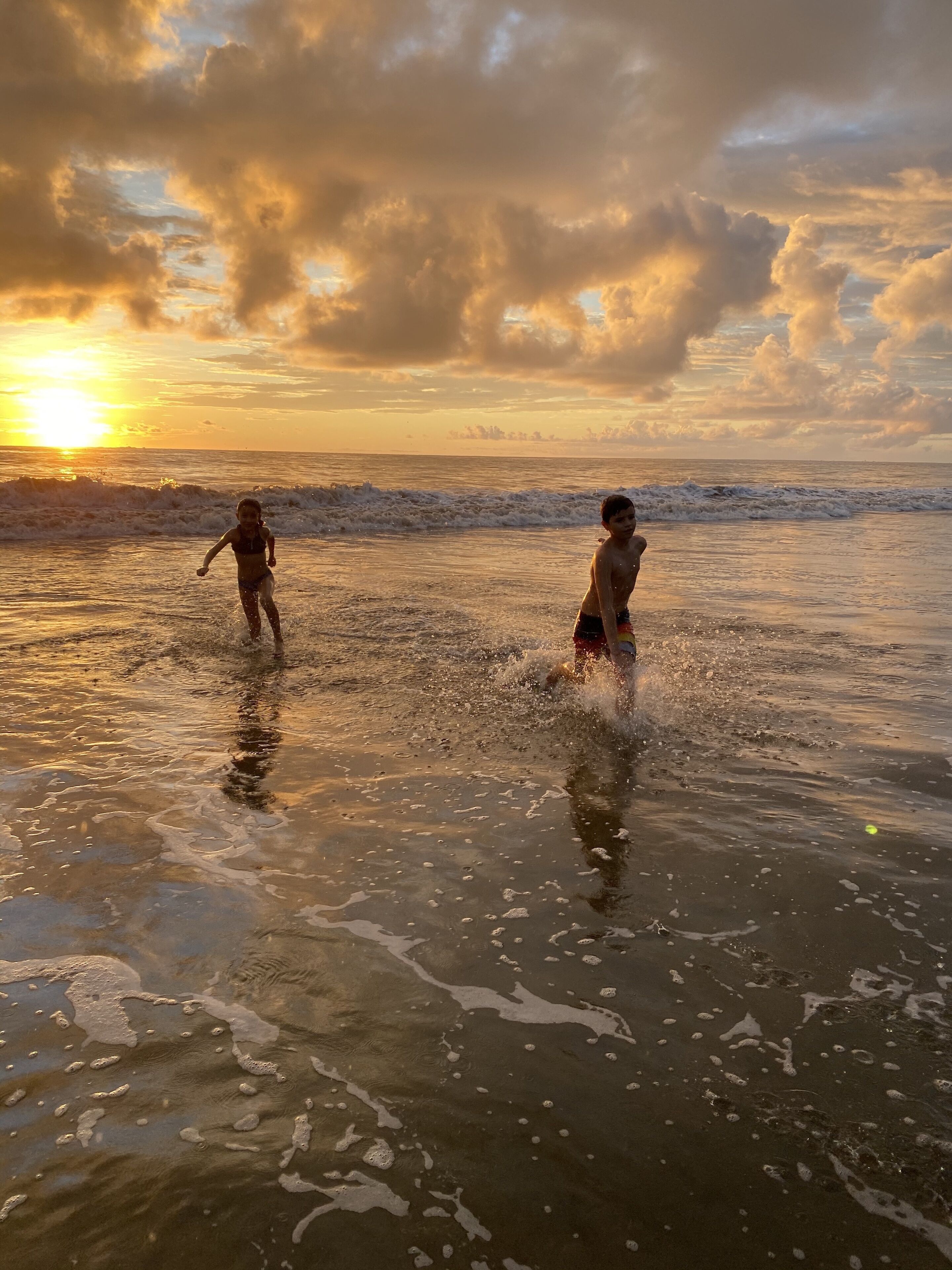 Two individuals playing in the water at sunset.
