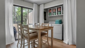 Cocina compacta con lavadora, una mesa de comedor y sillas, y vistas a zonas verdes.
