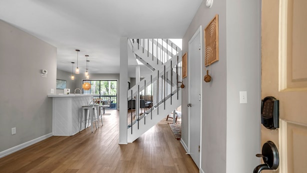 Una cocina moderna con una isla central, una escalera que lleva a una zona superior, y vistas al exterior.