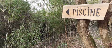 A wooden sign with an arrow pointing left, labeled 'PISCINE'.