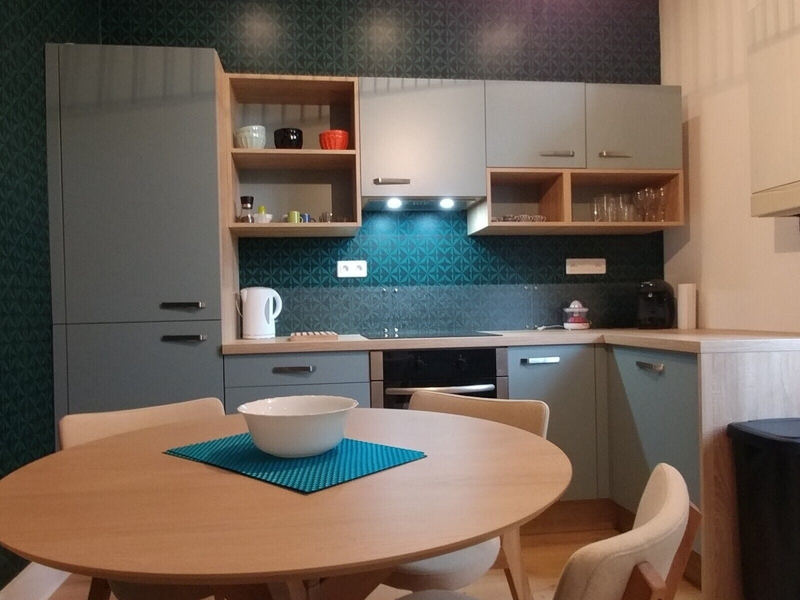 Una cocina compacta con una mesa redonda para comer, una cafetera y un hervidor.