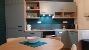 Una cocina compacta con una mesa redonda para comer, una cafetera y un hervidor.
