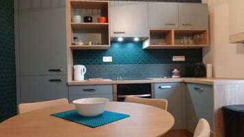 Una cocina compacta con una mesa redonda para comer, una cafetera y un hervidor.