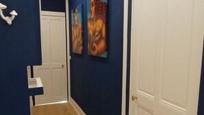 Un pasillo con paredes azules, suelo de madera y dos cuadros colgados.