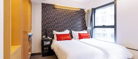 Una habitación de hotel con cama, mesita de noche, armario, ventana y pared con diseño.