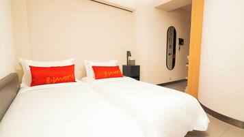 A hotel room with a bed, a nightstand, a mirror, and a door leading to another room.