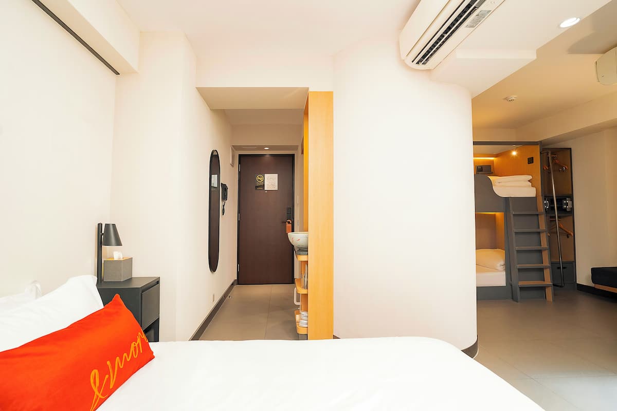 A hotel room with a bed, a nightstand, a desk, a bathroom with a shower, and a staircase.