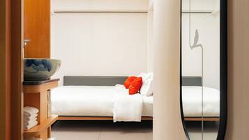Una habitación de hotel moderna con cama, un espejo y una repisa de madera con artículos de aseo.