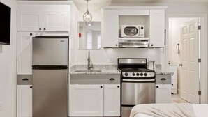 A compact kitchen with a refrigerator, stove, microwave, and sink.