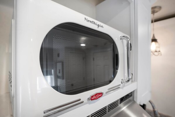 A white microwave oven with a perforated window and a brand name visible.