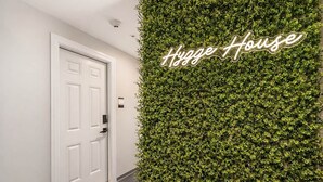 A hallway with a white door and a wall covered in green foliage. - Oak Suite at The Hygge House (Newburyport)