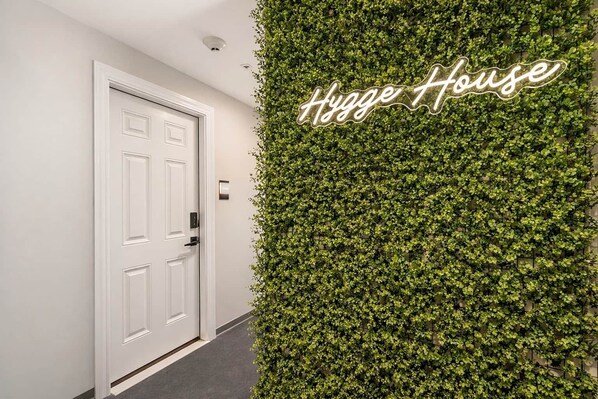 Un couloir avec une porte blanche et un mur recouvert de feuillage vert.