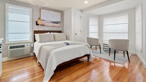 A spacious bedroom with a large bed, a chair, and a painting on the wall.