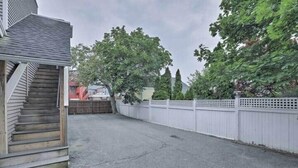 A residential driveway with a wooden staircase leading to a house, surrounded by a white fence and trees.