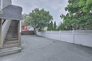 A residential driveway with a wooden staircase leading to a house, surrounded by trees and a white fence.