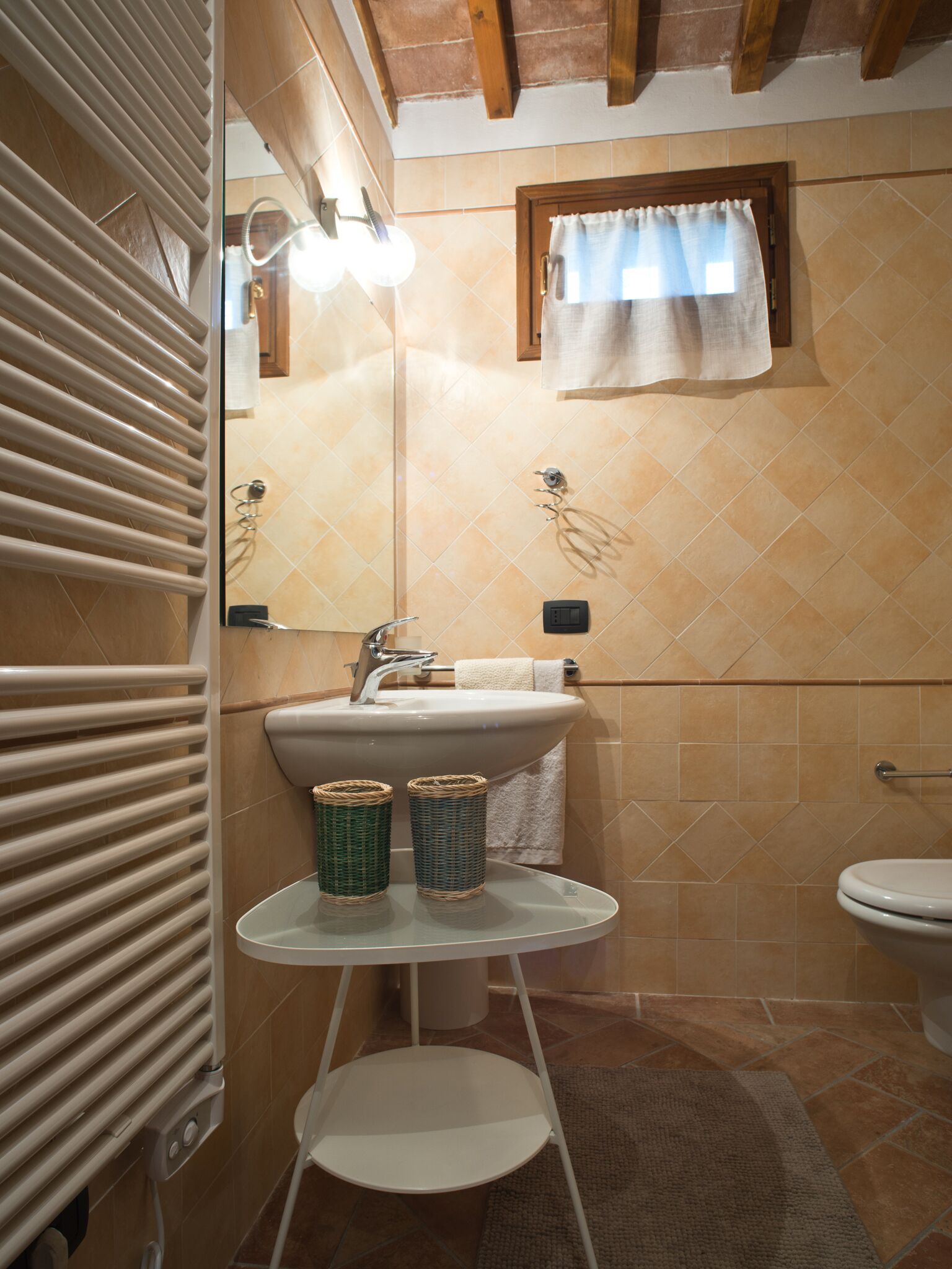 A bathroom with a sink, mirror, towel rack, and a small table with baskets.
