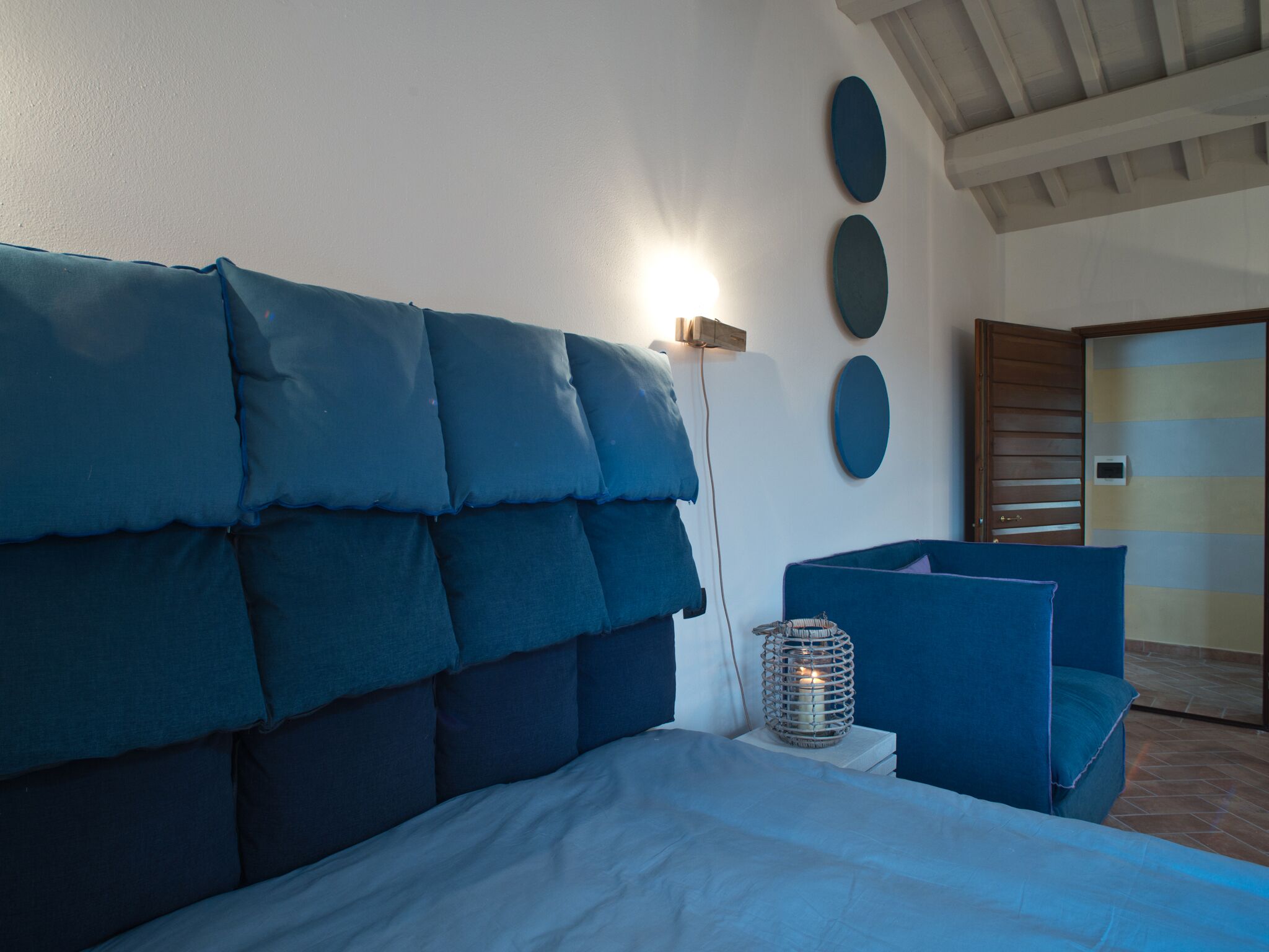 A bedroom with a large bed, a bedside table with a lamp, and a door with a striped pattern.