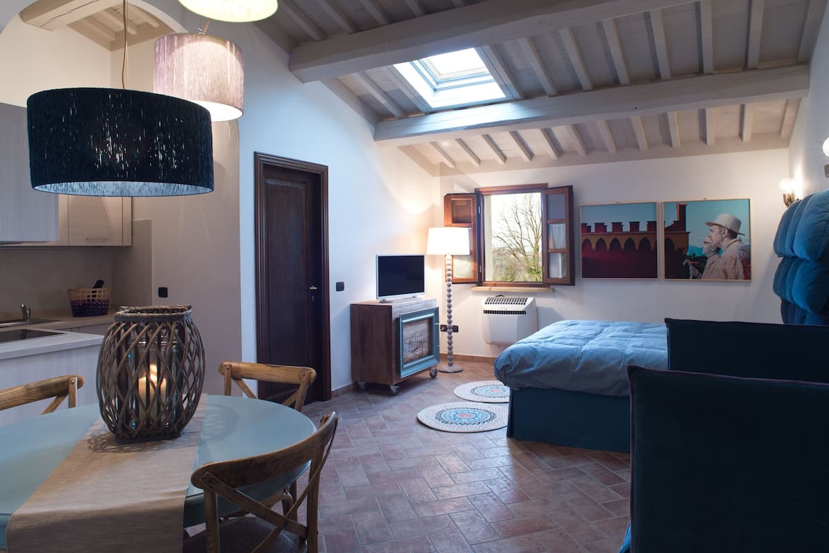 A spacious room with a dining area, a bed, and a television.