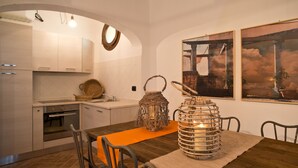 A modern kitchen with white cabinets, a dining table with chairs, and a large window. - San Ruffino Apartments (Casciana Terme Lari)