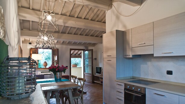A modern kitchen with a central island, built-in appliances, and a dining area with a table and chairs. - San Ruffino Apartments (Casciana Terme Lari)