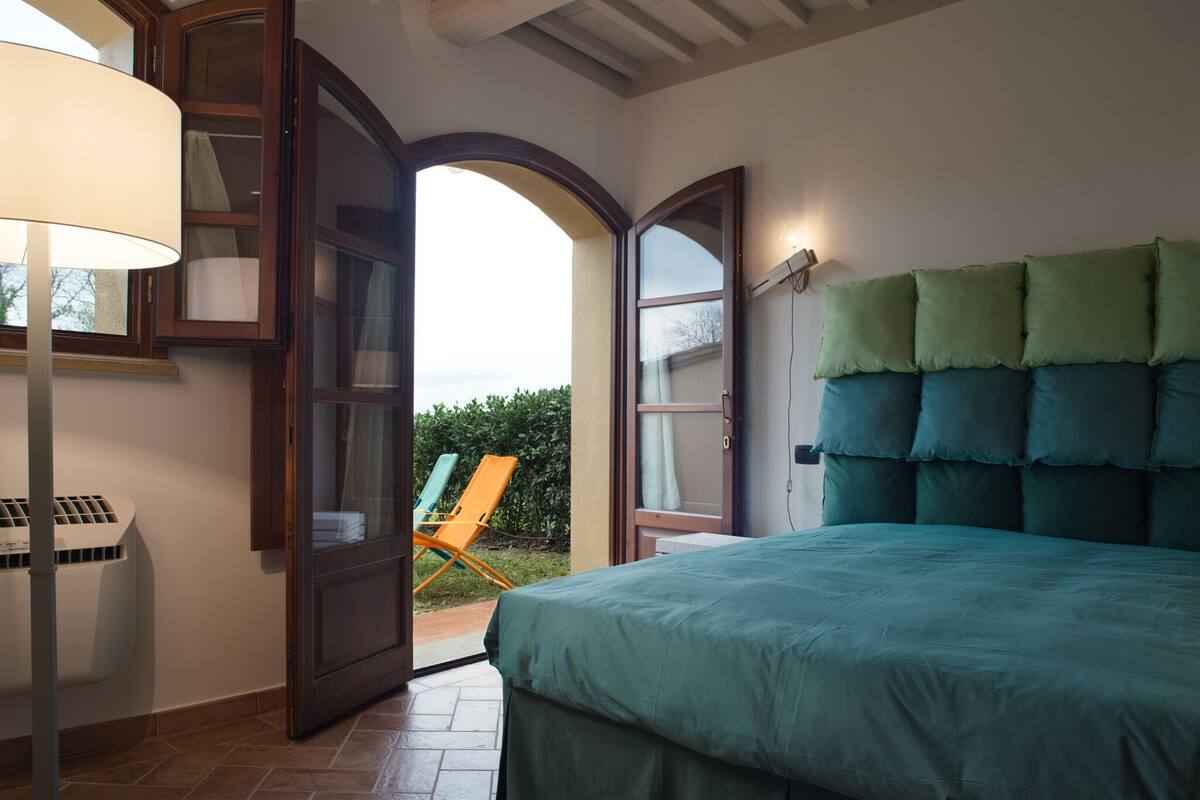 A bedroom with a bed, a chair, and a window.