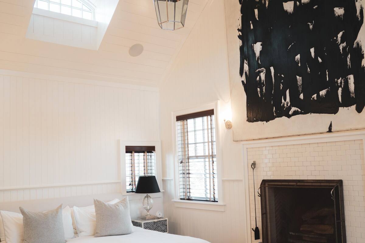 A bedroom with a large bed, a fireplace, and a skylight.