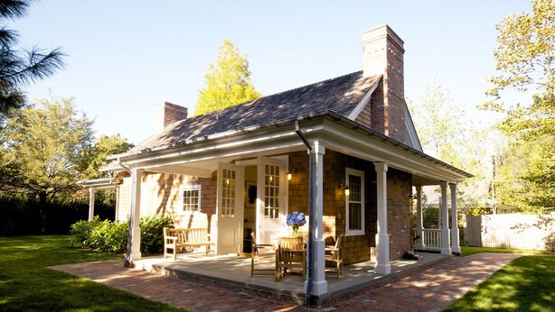 A brick house with a covered porch, a chimney, and a well-maintained lawn. - The Reform Club (Amagansett)
