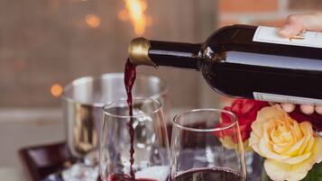 Una botella de vino tinto sirviéndose en dos copas sobre una mesa con mantel estampado de estrellas.