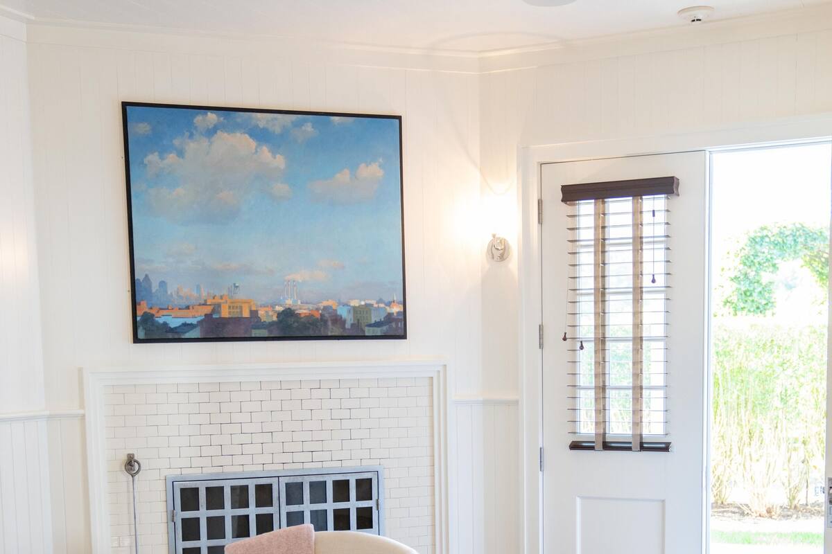 A living room with a fireplace, a door with a window, and a painting on the wall.