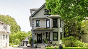 Ein zweistöckiges Haus mit Veranda, Garage und gepflegtem Rasen.