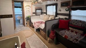 Un intérieur de camping-car accueillant, avec un coin cuisine, un espace salon doté d’un canapé et de coussins, et une petite table à manger.