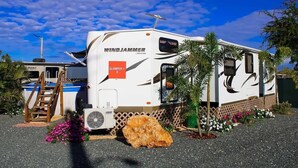 Un camping-car Windjammer équipé d’une échelle, d’un ventilateur et arborant le logo Glampers.