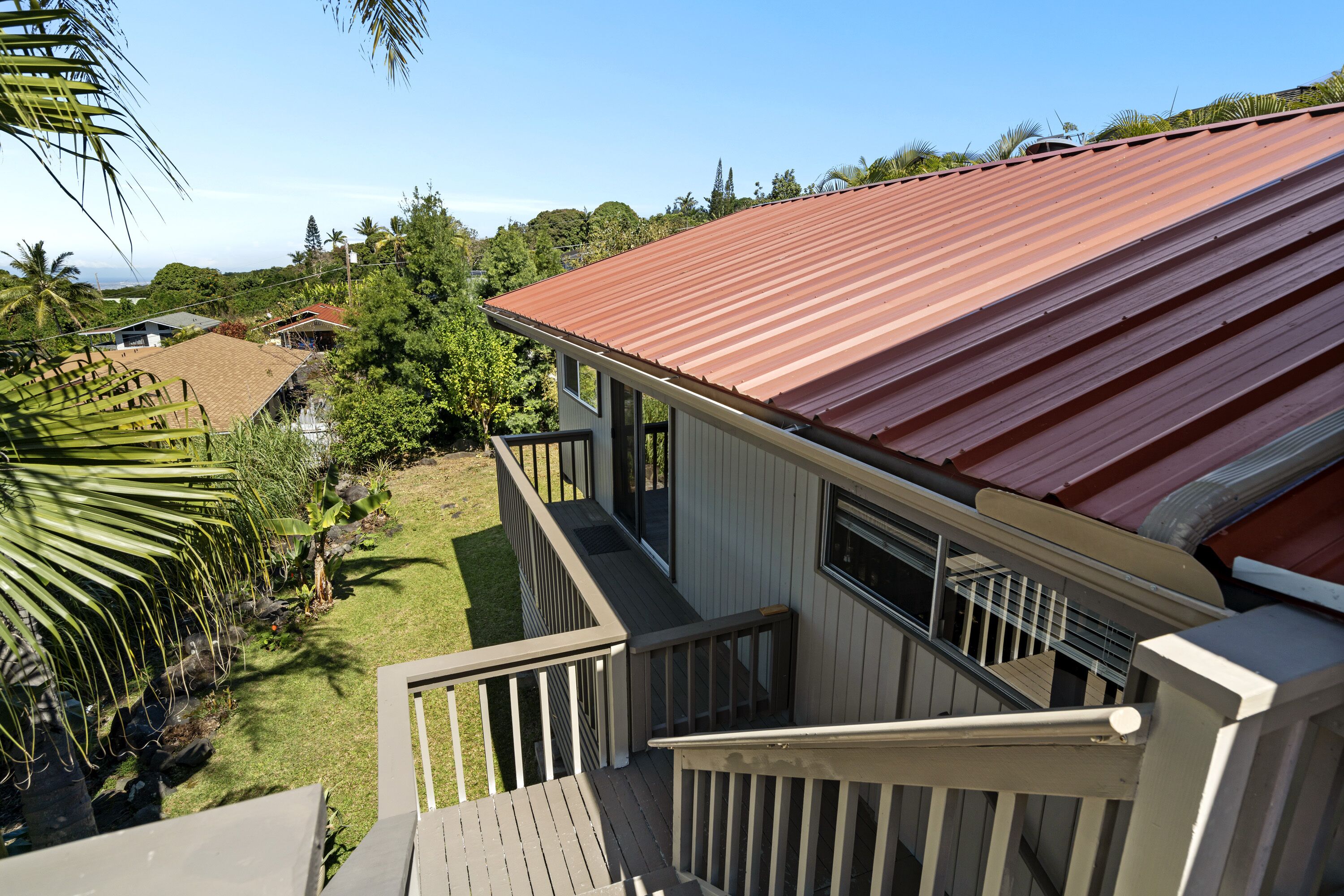 A residential building with a red metal roof, a wooden deck, and a small balcony.