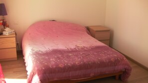 Quarto com cama, mesa de cabeceira, penteadeira e luminária.