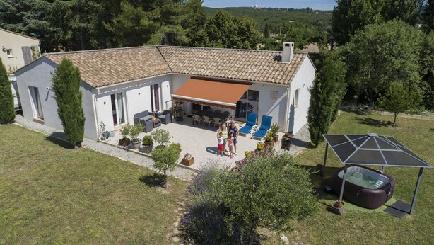 Ein Haus mit Ziegeldach, einer Terrasse mit Gartenmöbeln und einem Swimmingpool.
