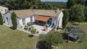 Uma casa com telhado de cerâmica, um pátio com móveis de exterior e uma piscina.
