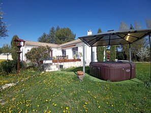 Uma casa com varanda, hidromassagem e um jardim com flores amarelas.
