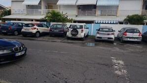A row of parked cars along a street with a building in the background. - Mezzanine À LA Marina (Saint-François)