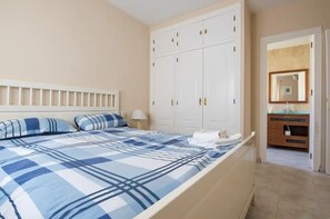 A bedroom with a large bed, a wardrobe, a bathroom with a mirror, and a bedside table. - 43813- 3 bedroom- Beautiful accommodation with private pool (velez malaga)
